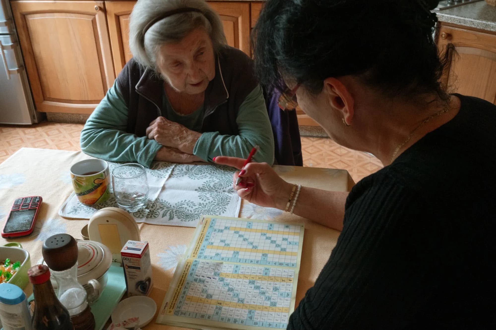 Two people working on a crossword together at a kitchen table